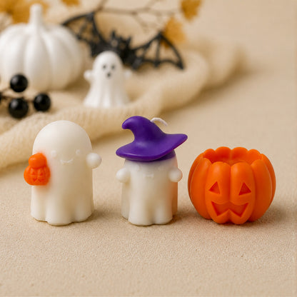 Trois bougies fantômes blanches et une citrouille orange en cire, décor d'Halloween